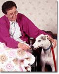 Woman in a wheelchair petting a Greyhound