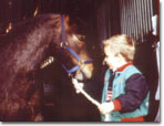 A small boy leading a pony